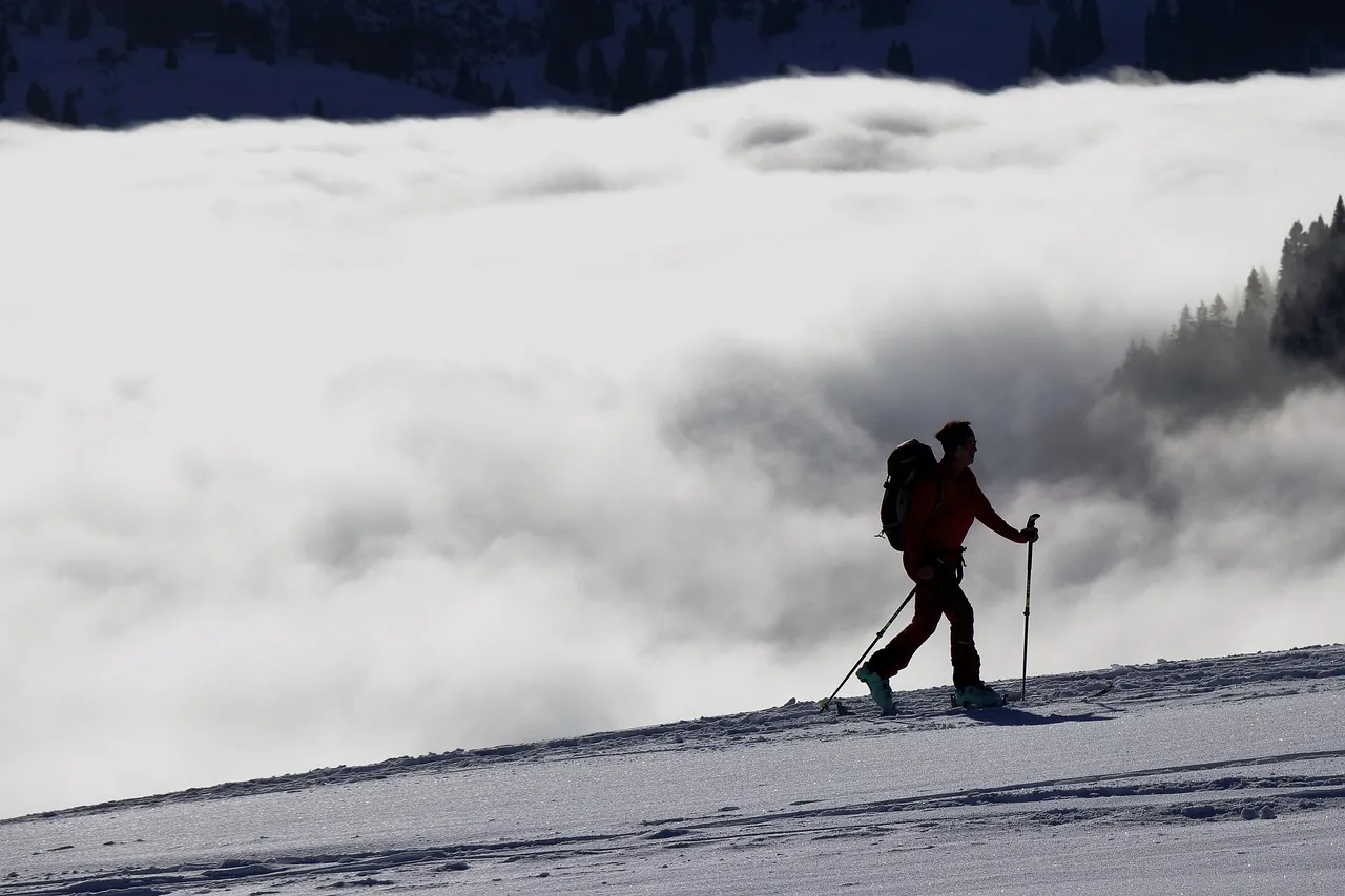 skitouren geher beim aufstieg in oberbayern, im hintergrund zieht der nebel über die berge
